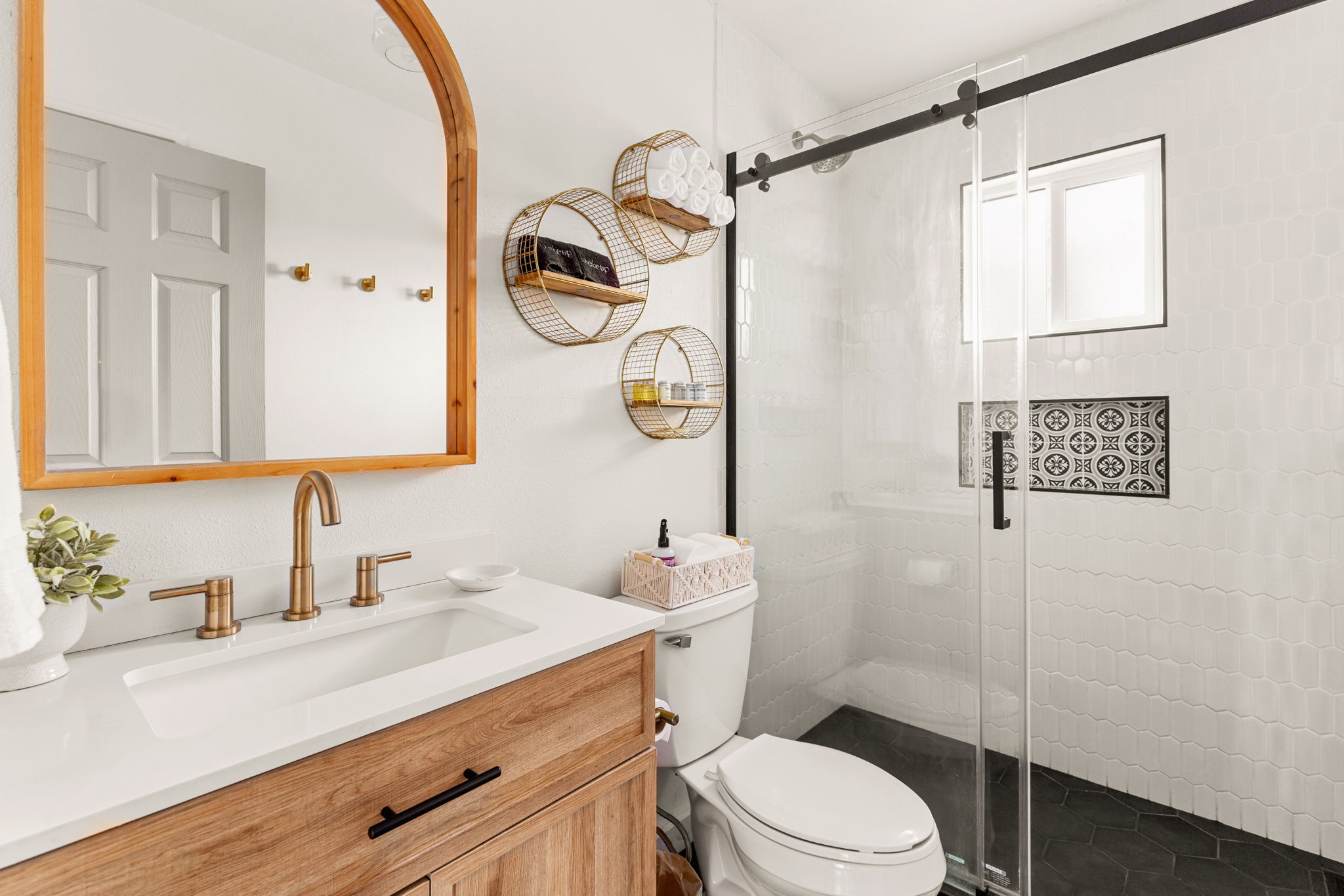 Renovated bathroom with arched mirror and gold fixtures